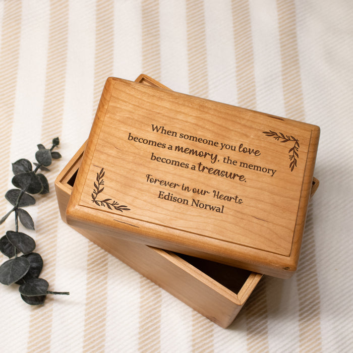 Wooden memory box with personalized engraved text on a striped fabric background