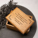 Wooden memorial keepsake box with engraved custom text on a dark surface with leaves.