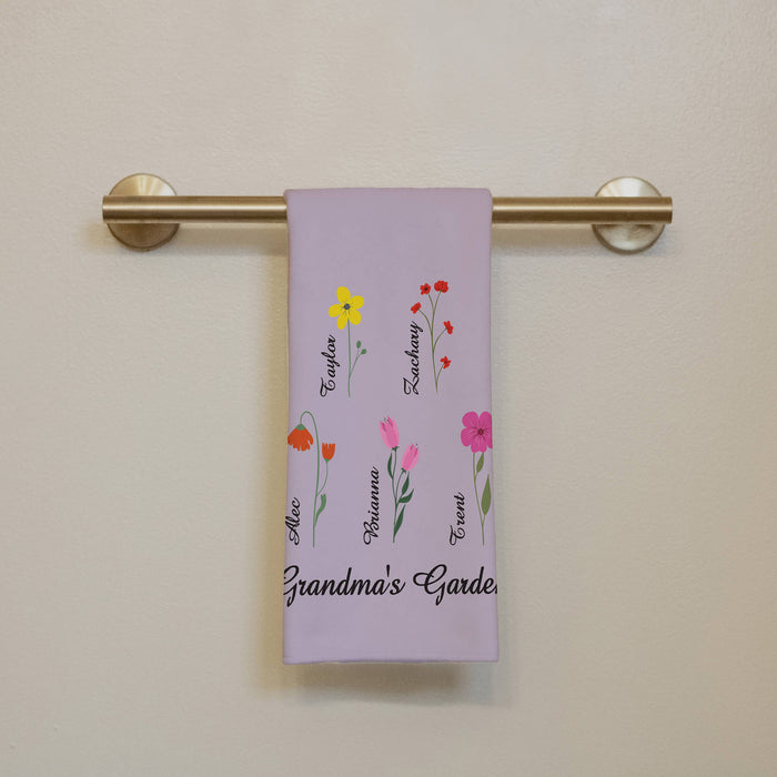 Floral-themed towel that says "Grandma's Garden" with names on a towel rack against a beige wall