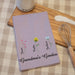 Purple towel with floral designs and text on a checkered tablecloth with a sugar container and whisk.