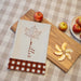custom Thanksgiving towel laying on a wooden charcuterie board with apple slices on it
