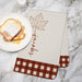 Fall maple leaf designed towel printed with a custom last name on a marble countertop next to a plate of french toast with syrup