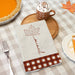 autumn leaf kitchen towel personalized with a custom last name on a Thanksgiving dinner table next to a pumpkin pie and hot chocolate