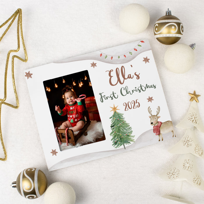 Christmas photo display with a photo of a baby and custom 'Baby's First Christmas 2025' text, surrounded by festive decorations.