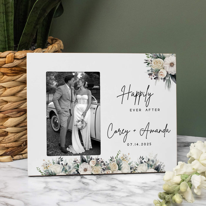 Personalized photo frame with floral wedding design and text, placed on a marble surface with decorative elements.