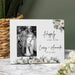 Personalized photo frame with floral wedding design and text, placed on a marble surface with decorative elements.