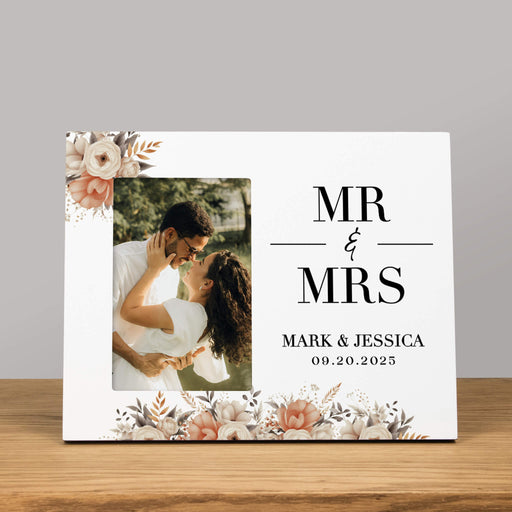 Personalized wedding photo album with 'MR & MRS' text and pink floral design on a wooden surface.