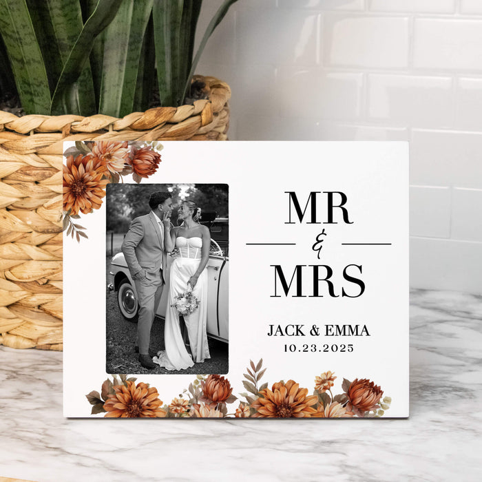 Personalized 'MR & MRS' sign with photo of couple and wedding date, placed on a marble surface with a plant in the background.