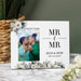 Personalized photo frame with 'MR & MR' text and a couple's photo, placed on a marble surface with decorative elements.
