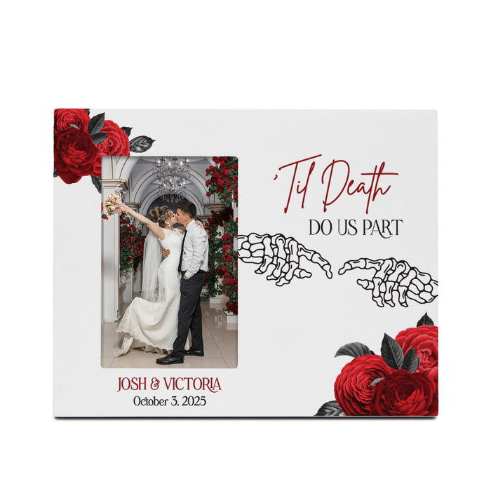 A square white wedding keepsake photo frame with red rose illustrations in the corners, skeleton hands graphic, and the text 'Til Death Do Us Part' and 'Josh & Victoria October 3, 2025'. A custom wedding photo of a couple kissing is displayed in the center cutout.