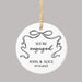 'We're engaged' Christmas ornament personalized with names and a date and decorated with a black coquette bow