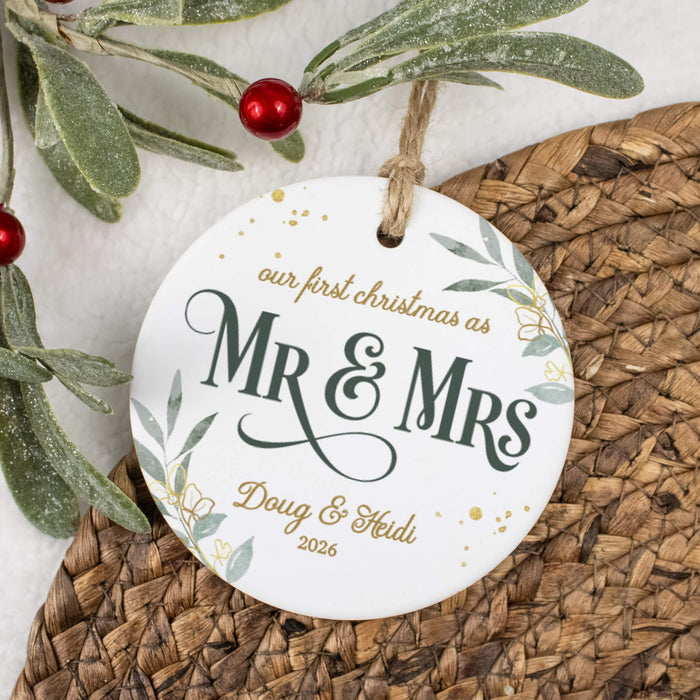 'Our first Christmas as Mr & Mrs' ornament laid on a wicker placemat next to a holly branch