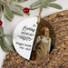 A personalized oval memorial hanging ornament with a photo of a woman and the text 'In Loving Memory Maggie Smith 1963 - 2025', styled on a woven placemat with greenery and red berries.