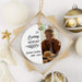 A personalized round hanging memorial ornament displayed inside a square-shaped gift box. The ornament has a white background with black text reading 'In Loving Memory' and the name 'Justin Corbin 2008-2025,' plus a printed photo of a man in a brown jacket beside a stack of pancakes.