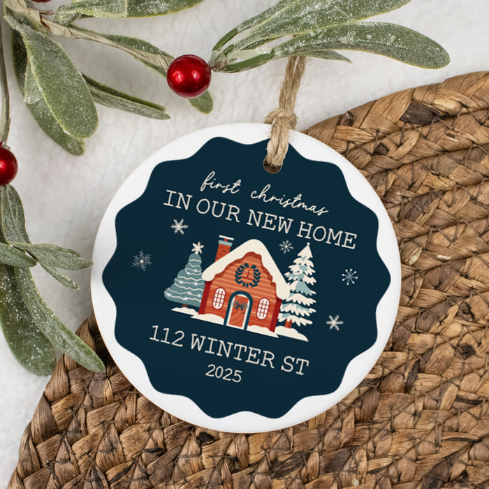 Decorative christmas ornament keepsake for new home with a house illustration and text on a woven surface with greenery.