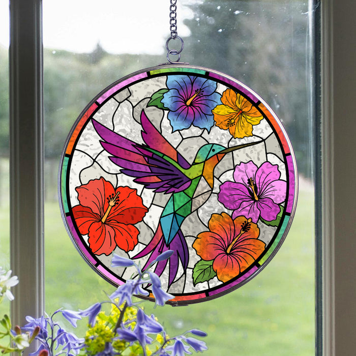 Stained glass acrylic suncatcher with a colorful hummingbird and flowers hanging on a window.