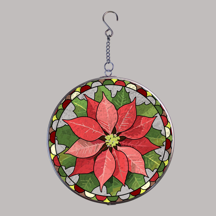 A circular hanging suncatcher stylized with a poinsettia flower in red and pink tones with green leaves, outlined in a silver metal frame and suspended by a short chain from a hook.