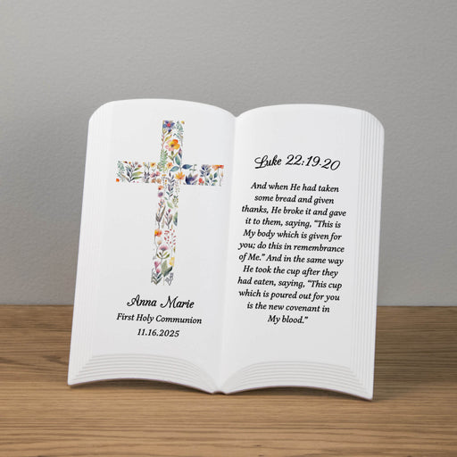 Ceramic book with floral cross design and personalized First Holy Communion text on a wooden surface