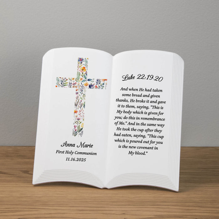 Ceramic book with floral cross design and personalized First Holy Communion text on a wooden surface