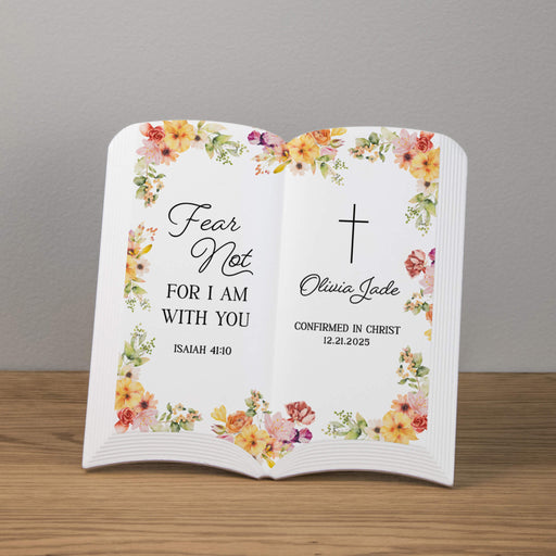 Personalized open ceramic book with floral design and religious text on a wooden surface.