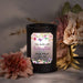 Black wax melt lamp with floral design and memorial text surrounded by flowers on a marble surface
