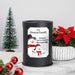 A black cylindrical wax warmer lamp with a custom printed label featuring snowman illustrations and the text 'The Henson Family, Family is forever because love never melts.' The lamp is styled on a marble surface with a small Christmas tree, red ornaments, and a potted poinsettia in the background.