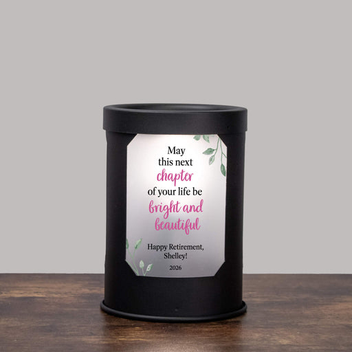 Black wax warmer lamp with a retirement design printed on the window on a gray background