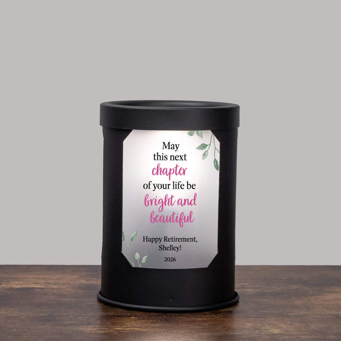 Black wax warmer lamp with a retirement design printed on the window on a gray background