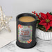A black cylindrical wax melt lamp with beige wax and a festive holiday label reading 'Wishing You Peace & Joy This Holiday Season' 'The Bowers.' The candle is styled on a marble surface with a red poinsettia, a white ribbed vase, and a decorative gold star in the background.