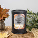 A matte black cylindrical wax warmer with a fall-themed label reading 'grateful THANKFUL blessed' and showing white pumpkins among autumn leaves, styled on a woven mat with leaves and greenery in the background.