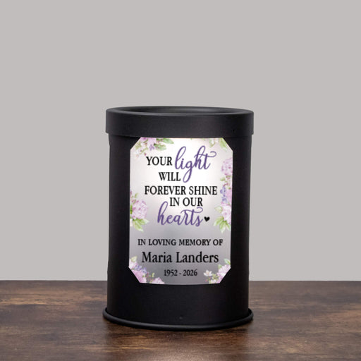 black wax melt warmer with floral design and memorial message with personalized name and years of life sitting on a wood table with a gray background