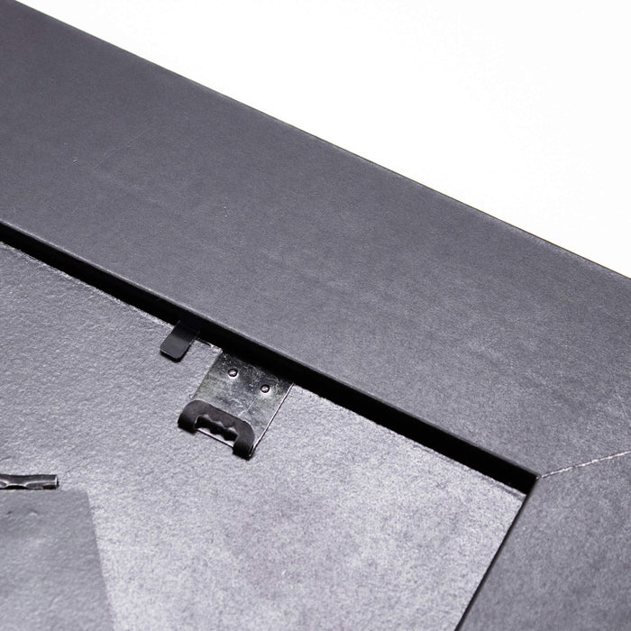 Close up of a black picture frame showing the hanger hook on a white background
