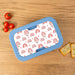 Personalized rainbow lunch box in blue on a wooden surface with tomatoes and crackers.