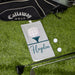 Golf towel with name on it, golf bag, golf club, and balls on grass