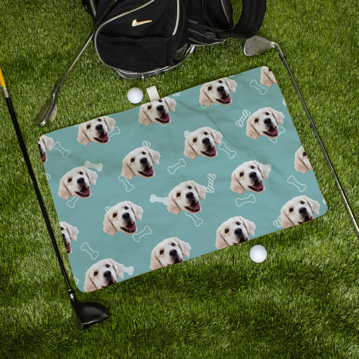 Golf towel with a pattern of dog faces on a green grass background