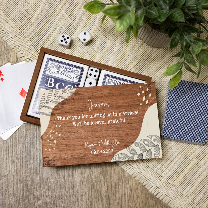 Personalized wooden card with wedding officiant proposal text, playing cards, and dice on a textured surface.