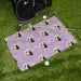 Pink golf towel with dog pattern on grass next to golf equipment