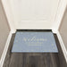 Decorative doormat with 'Welcome to Dorm Room' text on a wooden floor.