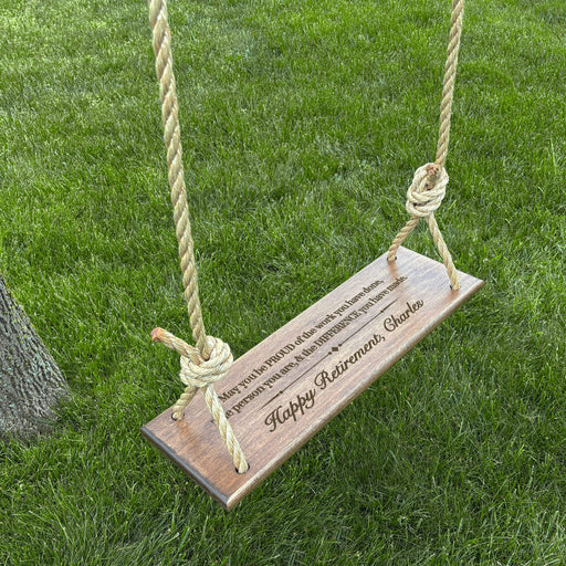 Wooden swing with a personalized retirement message hanging from a tree