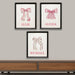 Three framed prints with pink bows and names on a wall above a wooden shelf.