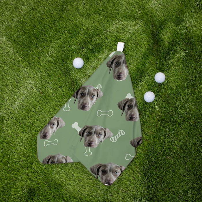 Green golf towel with dog faces and bones pattern on grass