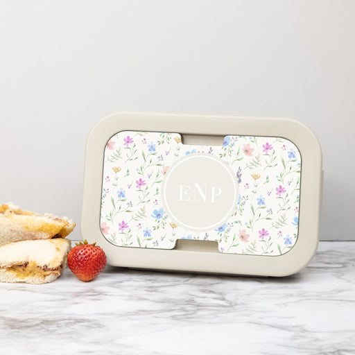 Monogrammed floral lunch box on a countertop next to a sandwich and strawberry