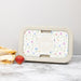 Monogrammed floral lunch box on a countertop next to a sandwich and strawberry