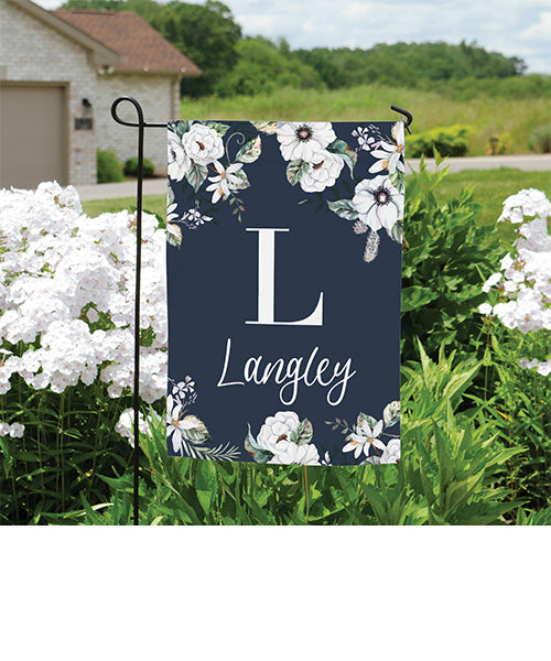 Garden flag with floral design and family name in a garden setting