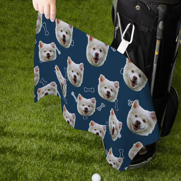 Golf towel with a pattern of a white dog's face on a blue background, held by a person on grass.