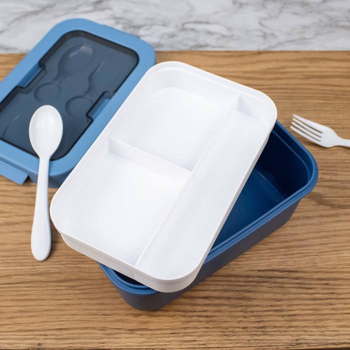 Blue and white lunch box with a spoon and fork on a wooden surface