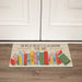 Personalized classroom doormat with colorful books design and text on a wooden floor.