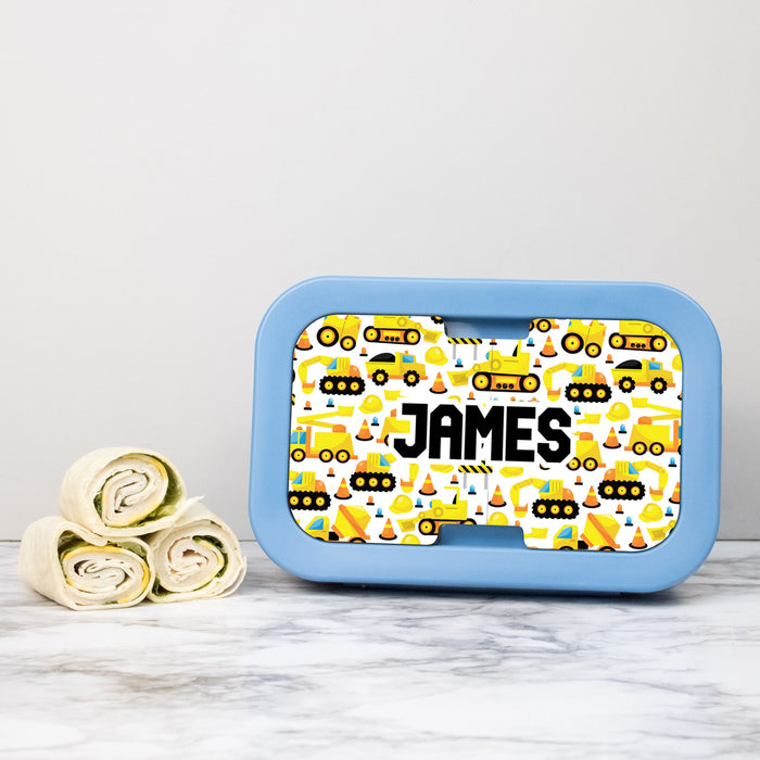Blue lunch box with construction vehicle pattern and name on a light gray background