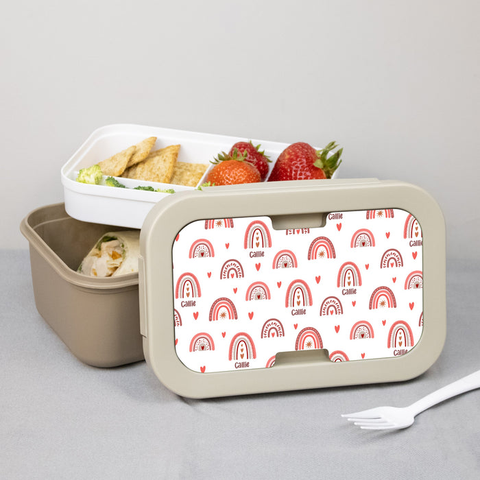 Lunch box with a patterned rainbow lid containing snacks on a gray background