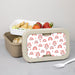Lunch box with a patterned rainbow lid containing snacks on a gray background